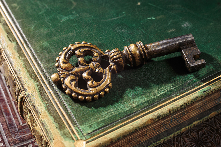 Antique bronze key with patina on ancient books symbolizing the leveraging of new technologies while maintaining high standards based upon old fashion values.