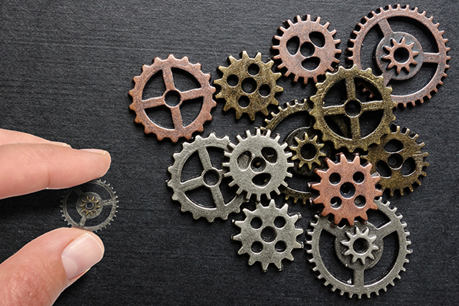 Human hand adding a spur gear representing a microservice to a group of gears as microservices.